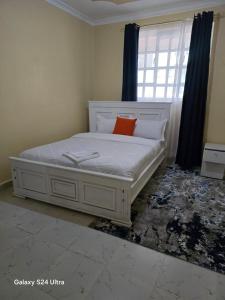 a bedroom with a white bed with an orange pillow at The comfort 2 bedrooms pioneer in Eldoret +3 photos