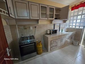 a small kitchen with a stove and a microwave at The comfort 2 bedrooms pioneer in Eldoret