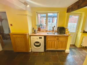 a kitchen with a sink and a washing machine at Bumblebee Cottage in Knowle