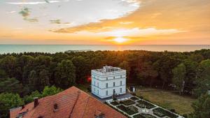 an aerial view of a white building with the sunset in the background at Vila Komoda in Palanga