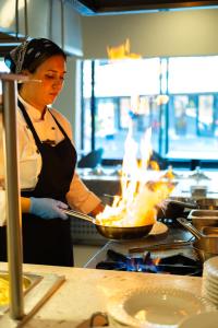 a woman in a kitchen preparing food on a stove at The X Belek in Belek