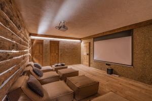- un salon avec un canapé et un écran de projection dans l'établissement Dolomites Luxe Cesa Del Louf, à Arabba