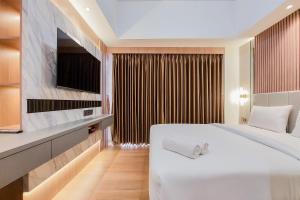 sypialnia z dużym białym łóżkiem i telewizorem w obiekcie Simply Look and Comfort Studio Room at Casa de Parco Apartment By Travelio w mieście Tangerang +8 zdjęć
