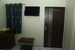 a room with a refrigerator and a television on a wall at Maa Rewa Homestay in Sānāwad