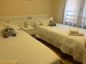 two teddy bears sitting on two beds in a room at Apartamentos El Espolón in Logroño