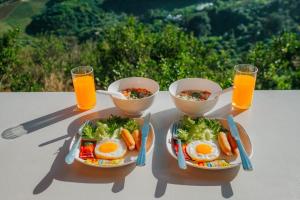 a table with two plates of food and two glasses of orange juice at ไร่กัลยา โฮมสเตย์ in Ban Thung Phan Ha
