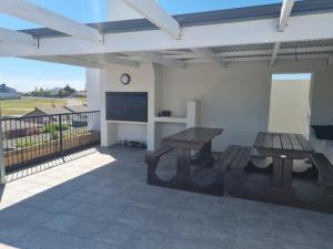 a patio with two picnic tables and a flat screen tv at Astros Lodge in Cape Town