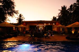 a swimming pool in front of a house with umbrellas at LalaGalu - Beachfront EcoCabins in Diani Beach