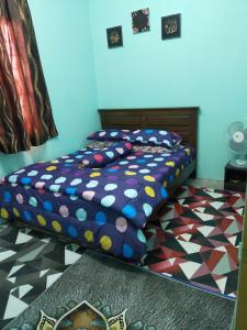 a bedroom with a bed with a colorful comforter at Dinaz Homestay Taman Limbungan Permai Melaka in Melaka