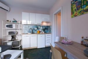 a kitchen with white cabinets and a table in a room at Apartment Lauro Opatija, ground floor, parking, near sea in Opatija +10 photos