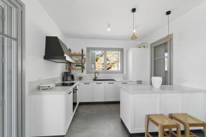Una cocina blanca con gabinetes blancos y una ventana. en Seahorse Villa, en Makrotándalon