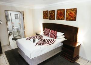 a bedroom with a bed with red and white pillows at Ehrlichpark Lodge self catering and spa in Bloemfontein +1 photo