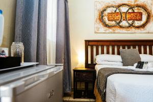 a hotel room with a bed and a television at Ehrlichpark Lodge self catering and spa in Bloemfontein