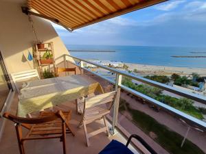 un balcone con tavolo e sedie e vista sulla spiaggia di Bel appartement vue mer a Palavas-les-Flots