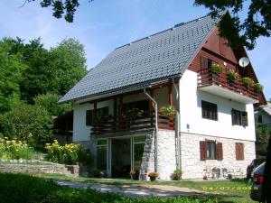une maison blanche avec un toit gris et des fenêtres dans l'établissement Vila Vuk, aux lacs de Plitvice