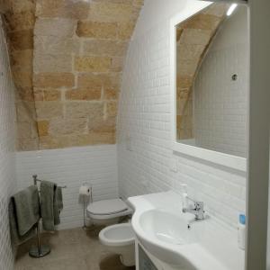 a white bathroom with a sink and a toilet at Casa vacanza nel cuore della pietra in Barletta
