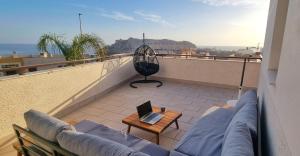 ein Balkon mit einer Couch und einem Laptop darauf in der Unterkunft PREMIUM Magníficas Vistas Panorámicas con Terraza - By Aloha Palma in Águilas