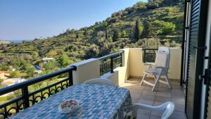 a balcony with a table and chairs and a mountain at Το Μπαλκόνι της Ξανθής in Evdilos