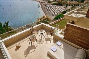 a balcony with chairs and a table and a view of a beach at Lindos Royal Resort in Líndos