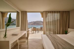 a hotel room with a bed and a desk and a window at Lindos Royal Resort in Líndos