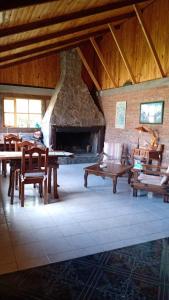 ein Wohnzimmer mit einem Steinkamin sowie Tischen und Stühlen in der Unterkunft Hostería Altas Cumbres in El Chalten