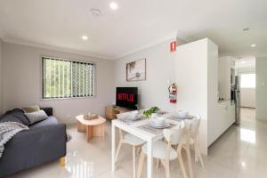 a living room with a couch and a table with chairs at Smart Suites Self Check-in Apartments - Freney Park Disk Golf Course in Brisbane