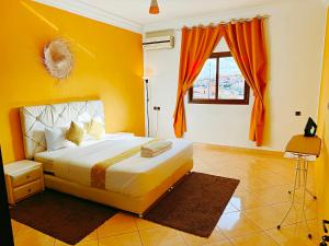 a bedroom with a bed with an orange wall at CHAY - Signature Apartments in Ouarzazate