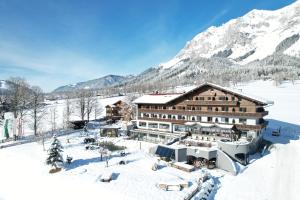 un hotel nella neve tra le montagne di Hotel Berghof a Ramsau am Dachstein