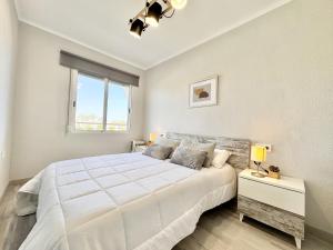 a white bedroom with a large bed and a window at Mediterranean Way - Pineda 1 in La Pineda +16 photos