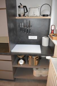 a kitchen with a shelf with utensils on it at Appartement-terrasse parking privé Meublé de Tourisme 4 étoiles in Belfort