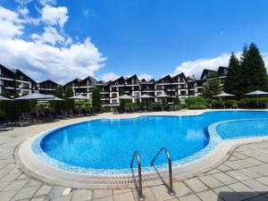 a swimming pool at a resort with chairs and umbrellas at Aspen Resort Studio I306 in Razlog
