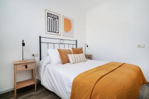 Un dormitorio con una cama con sábanas blancas y almohadas naranjas. en GALIHOST - Casa de Cruces, en Villanueva de Arosa