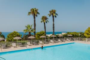 a person in a swimming pool with palm trees and chairs at Grand Hotel Riviera - CDSHotels in Santa Maria al Bagno