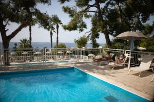 a swimming pool with people sitting in chairs and an umbrella at Grand Hotel Riviera - CDSHotels in Santa Maria al Bagno