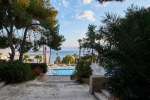 a pathway leading to a swimming pool with trees and the ocean at Grand Hotel Riviera - CDSHotels in Santa Maria al Bagno
