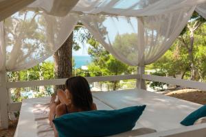 a woman sitting on a bed looking out at the ocean at Grand Hotel Riviera - CDSHotels in Santa Maria al Bagno