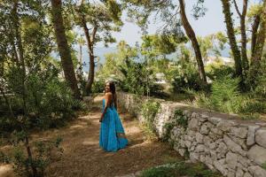a woman in a blue dress standing next to a stone wall at Grand Hotel Riviera - CDSHotels in Santa Maria al Bagno