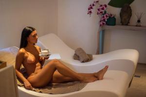 a woman in a bikini sitting on a couch with a cup of coffee at Grand Hotel Riviera - CDSHotels in Santa Maria al Bagno