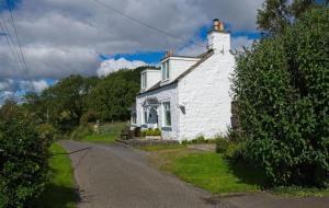 a white house with a chimney on a road at Bardristane Forge in Gatehouse of Fleet