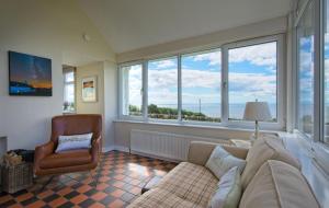 a living room with a couch and a chair and windows at Bardristane Forge in Gatehouse of Fleet