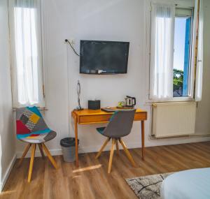 a desk and chairs in a room with a television on the wall at Hôtel Le Saint Pierre - Demeures & Châteaux , La Baule-Escoublac in La Baule