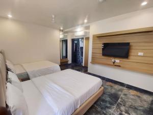 AmbajiArihant Hotel的一间卧室，配有两张床和一台平板电视