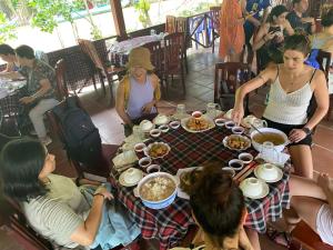 Un groupe de personnes assises autour d'une table avec de la nourriture dans l'établissement Giang Sơn Hotel 江山民宿范五老街胡志明市, à Hô-Chi-Minh-Ville
