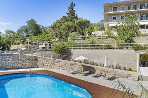 a swimming pool with chairs next to a building at Monte Verde apartments in Lixouri