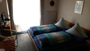 a bed with pillows on it in a room at Pension Arnold Neuenburg in Neuenburg am Rhein