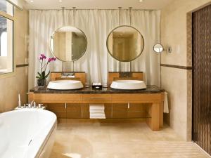 a bathroom with a tub, sink and mirror at Grand Hyatt Doha Hotel & Villas in Doha