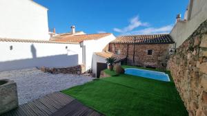 a small yard with green grass and a swimming pool at Sierra Serena in Baños de la Encina