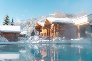 a log cabin in the snow with a swimming pool at DAS RONACHER Thermal Spa Hotel in Bad Kleinkirchheim