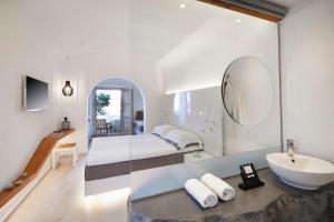 a bathroom with two beds and a sink and a mirror at Vrahos Boutique Hotel in Karavostasi
