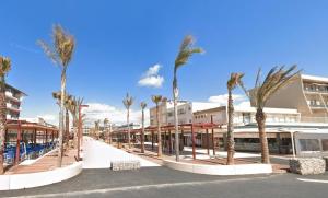 una strada con palme di fronte agli edifici di NP060-B08 Appartement 2 pièces 1 chambre, Narbonne Plage a Narbonne-Plage